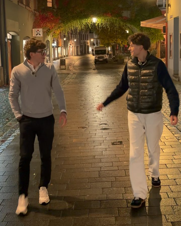 Jonathan und Valentin lachen sich in einer Altstadtgasse am Abend an.