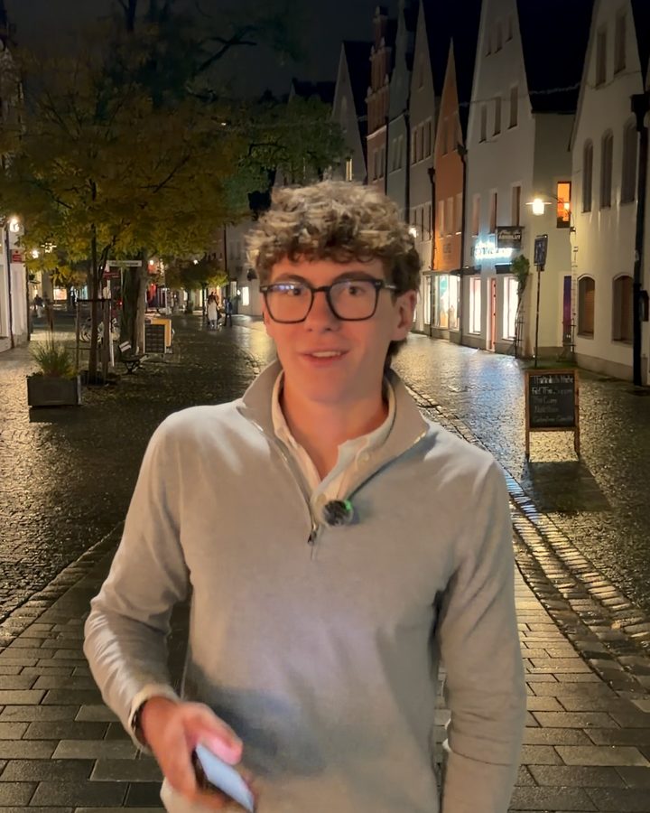 Jonathan in einer Fußgängerzone am Abend, er lächelt in die Kamera.