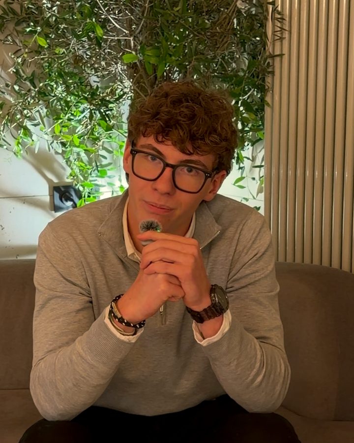 Jonathan sitzt auf einer Couch und schaut in die Kamera.