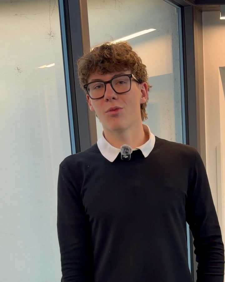 Jonathan in einem hellen Gang an einer Glaswand, er lächelt in die Kamera.