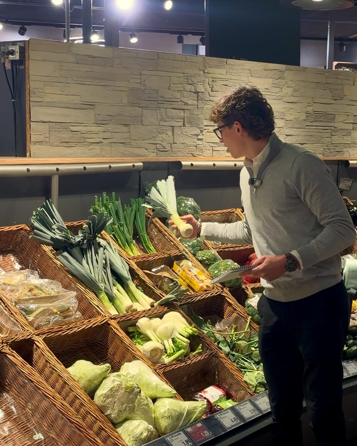 Jonathan legt in der Gemüseabteilung Lauch in den Korb.