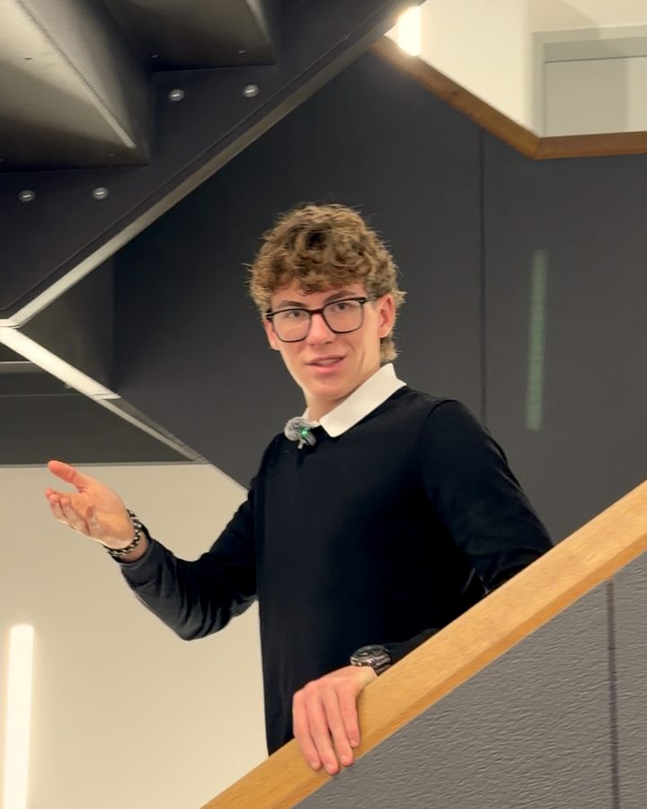 Jonathan steht im Treppenhaus und zeigt mit der Hand nach vorn.